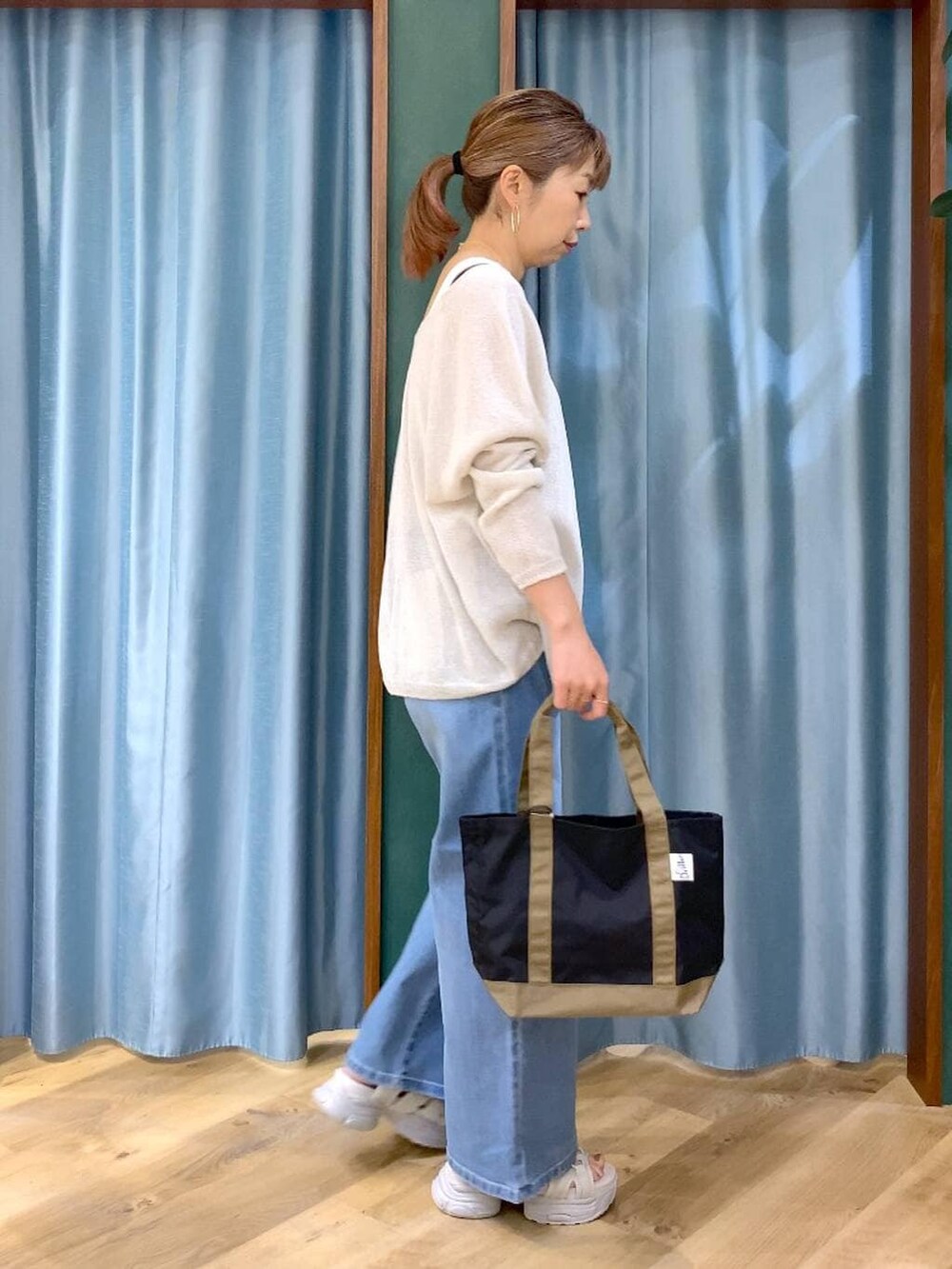 ブルー系のデニムパンツ、ホワイト系のタンクトップ、ホワイト系のニット/セーターを着用したレディースの春コーディネートの4枚目の写真