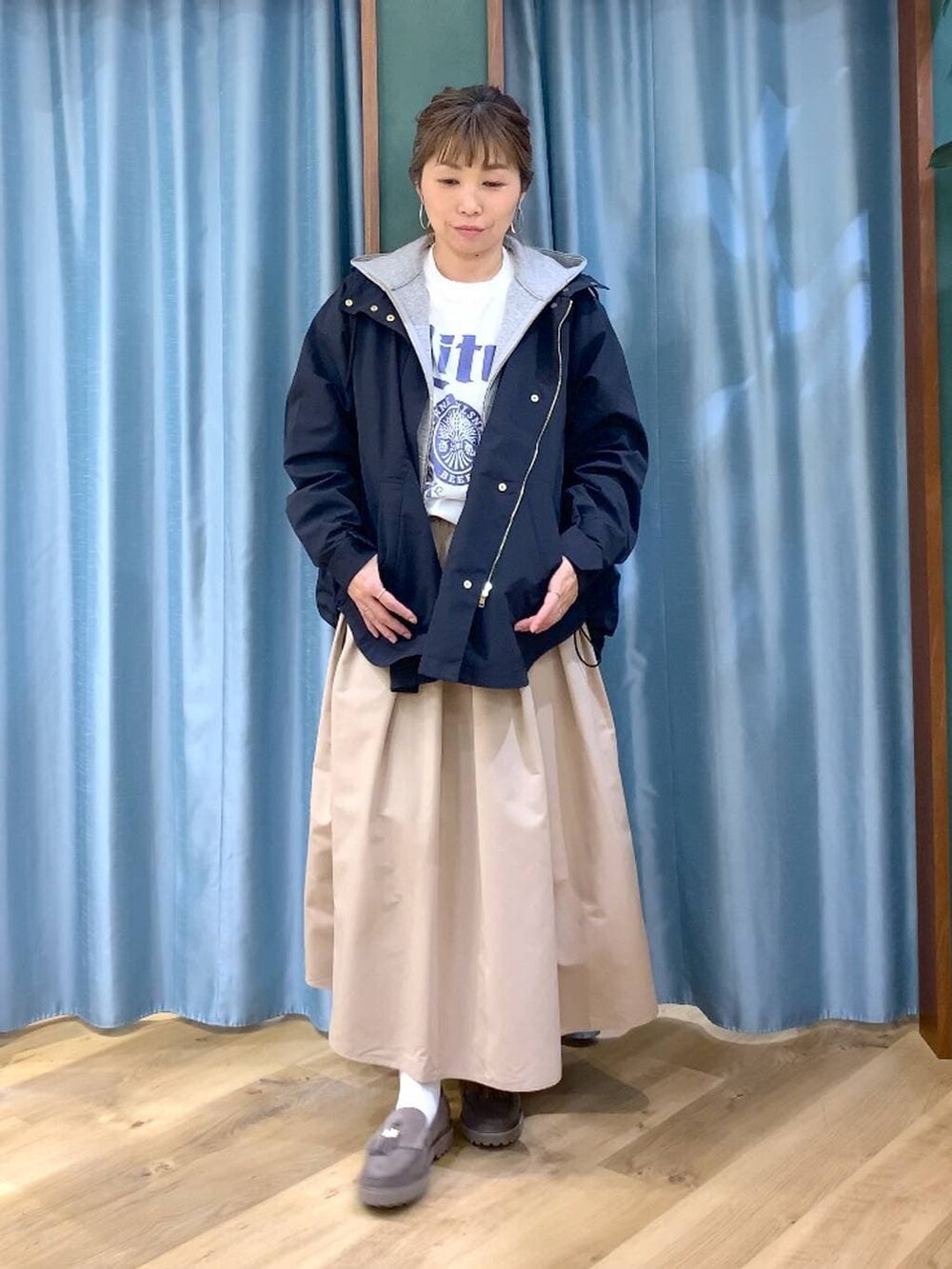 グレー系のローファー、グレー系のパーカー、ベージュ系のスカートを着用したレディースの春コーディネートの2枚目の写真