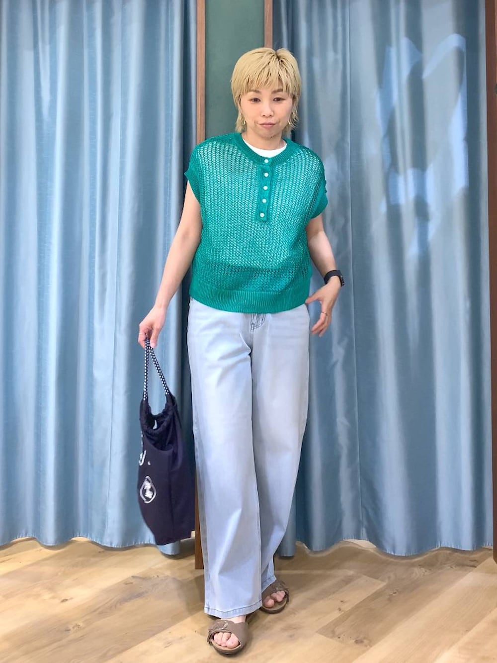 ホワイト系のTシャツ/カットソー、ブルー系のデニムパンツ、グリーン系のニット/セーターを着用したレディースの春コーディネートの4枚目の写真