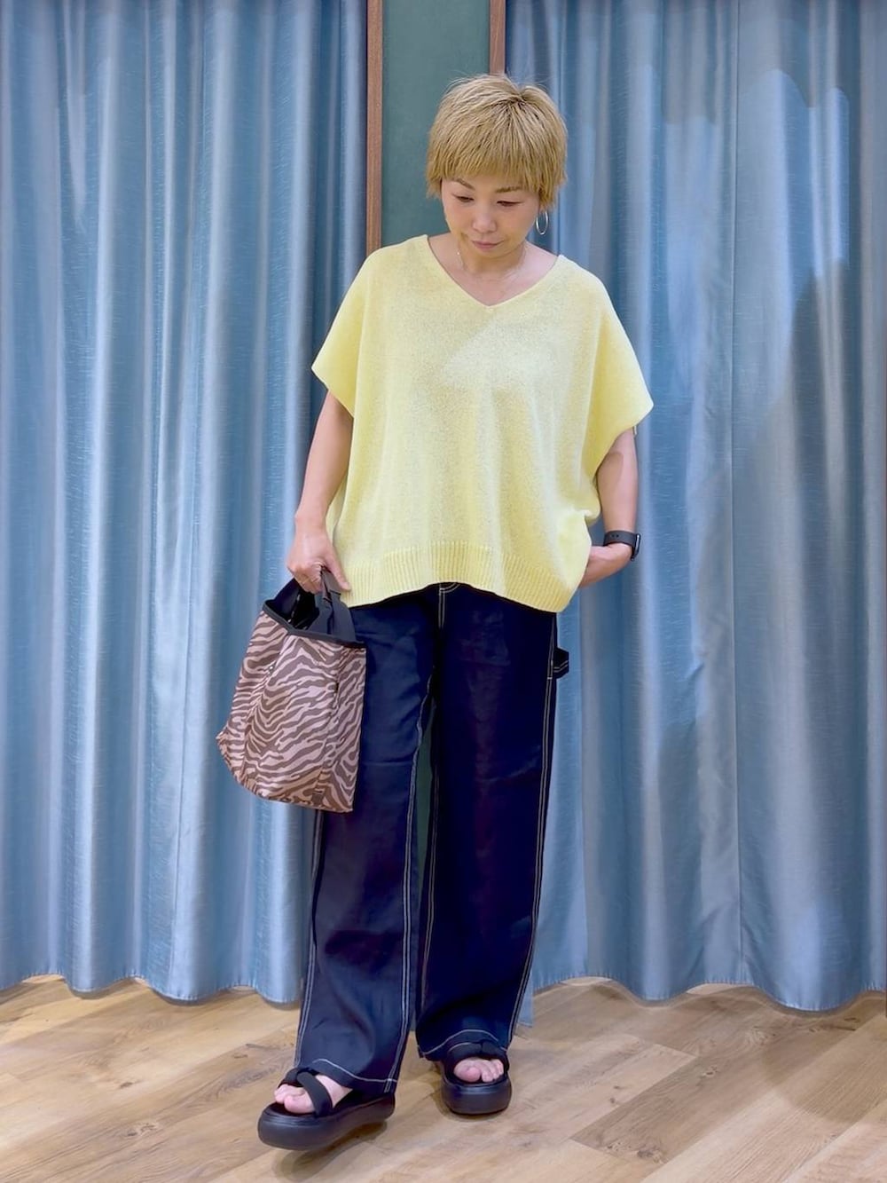 ブラウン系のトートバッグ、ブルー系のその他パンツ、ブラック系のサンダルを着用したレディースの夏コーディネートの2枚目の写真