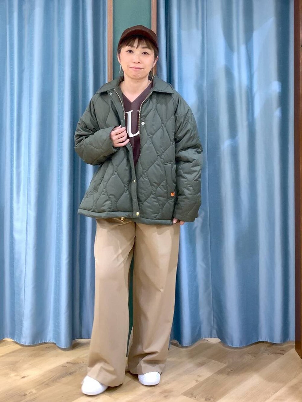 グリーン系のブルゾン、ブラウン系のニット/セーター、イエロー系のスラックスを着用したレディースの冬コーディネートの2枚目の写真