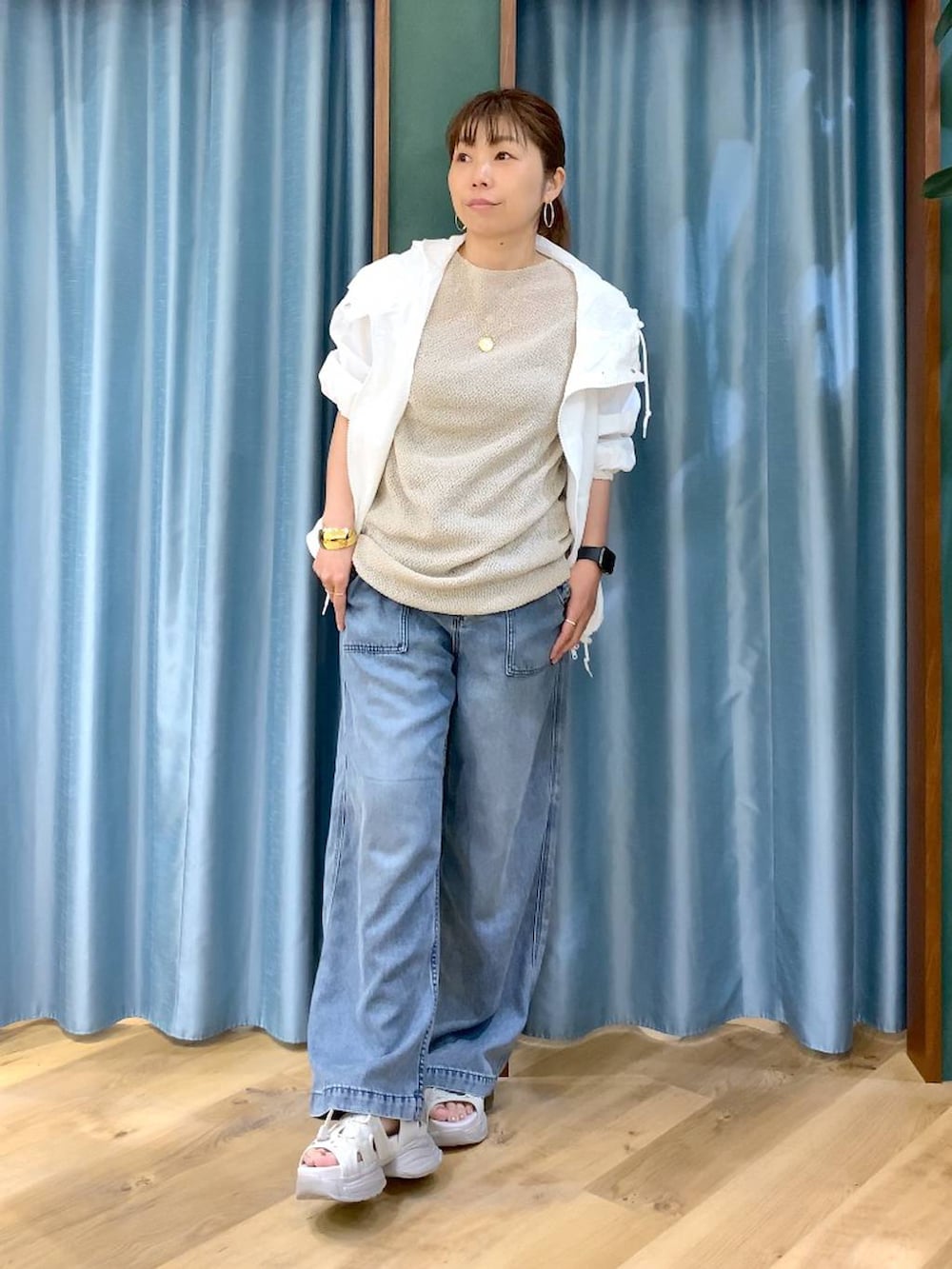 ブルー系のデニムパンツ、ホワイト系のブルゾン、グレー系のサンダルを着用したレディースの春コーディネートの2枚目の写真
