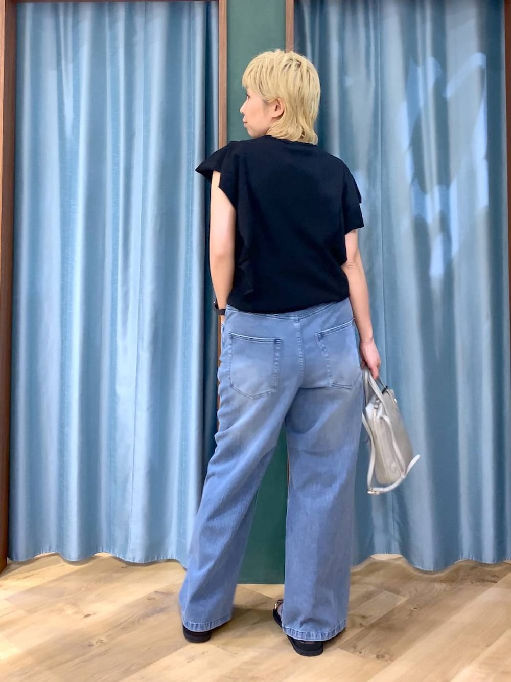 ブルー系のデニムパンツ、シルバー系のショルダーバッグ、ブラック系のニット/セーターを着用したレディースの夏コーディネートの7枚目の写真