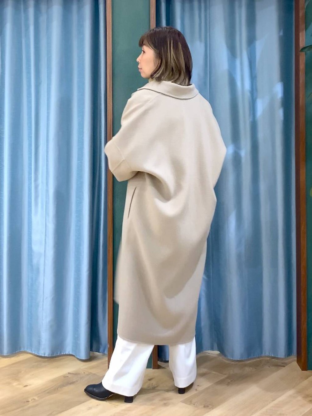 ベージュ系のニット/セーター、ベージュ系のチェスターコート、ブラック系のブーツを着用したレディースの秋コーディネートの4枚目の写真