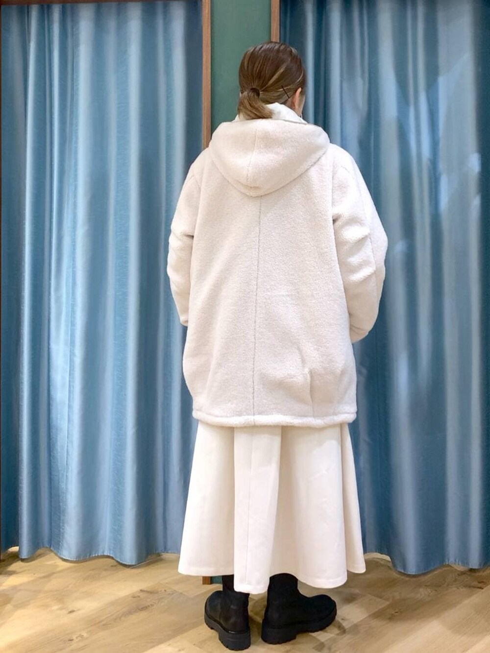 ブラック系のブーツ、ホワイト系のその他アウター、ホワイト系のスカートを着用したレディースの冬コーディネートの6枚目の写真