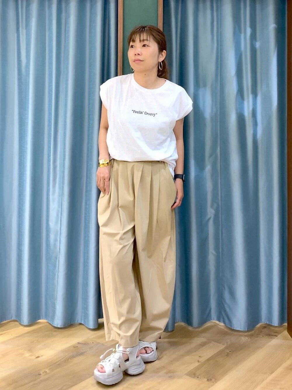 ベージュ系のその他パンツ、ホワイト系のTシャツ/カットソー、グレー系のサンダルを着用したレディースの春コーディネートの4枚目の写真