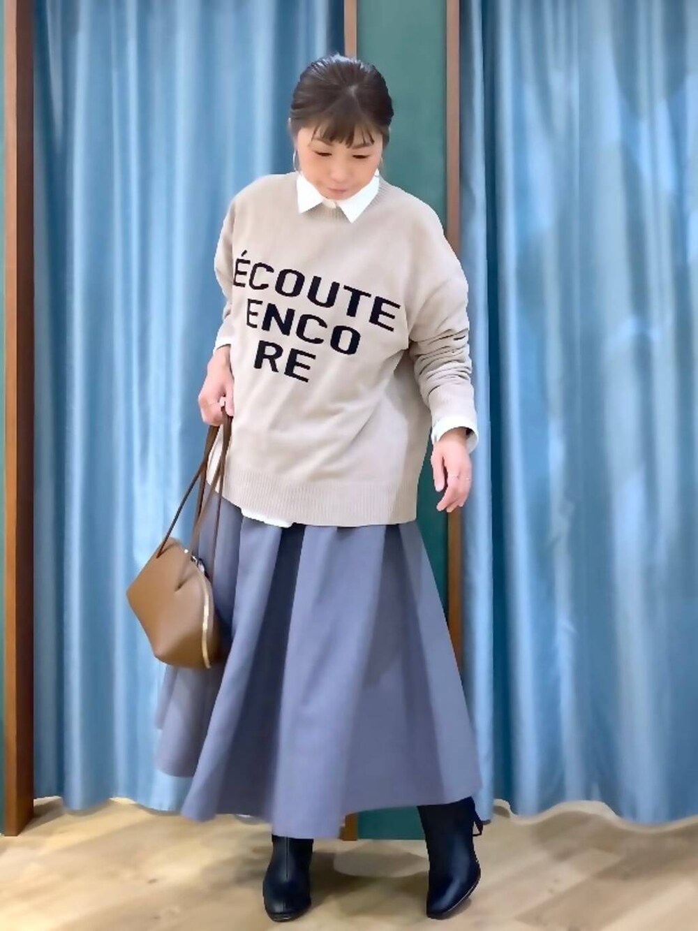 イエロー系のトートバッグ、ホワイト系のシャツ/ブラウス、ベージュ系のニット/セーターを着用したレディースの秋コーディネートの2枚目の写真