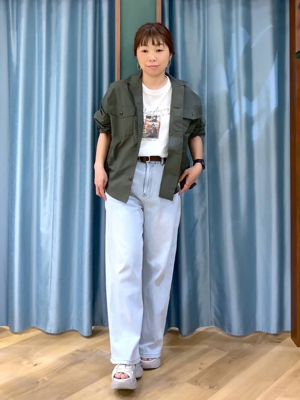 ブルー系のデニムパンツ、ホワイト系のTシャツ/カットソー、グレー系のサンダルを着用したレディースの春コーディネートの2枚目の写真