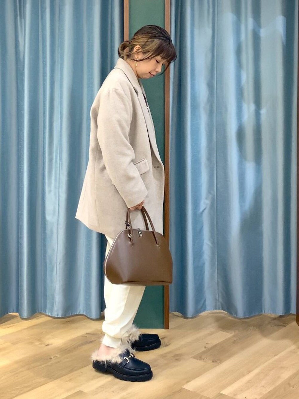 ブラウン系のトートバッグ、ブラウン系のニット/セーター、ベージュ系のピーコートを着用したレディースの秋コーディネートの3枚目の写真