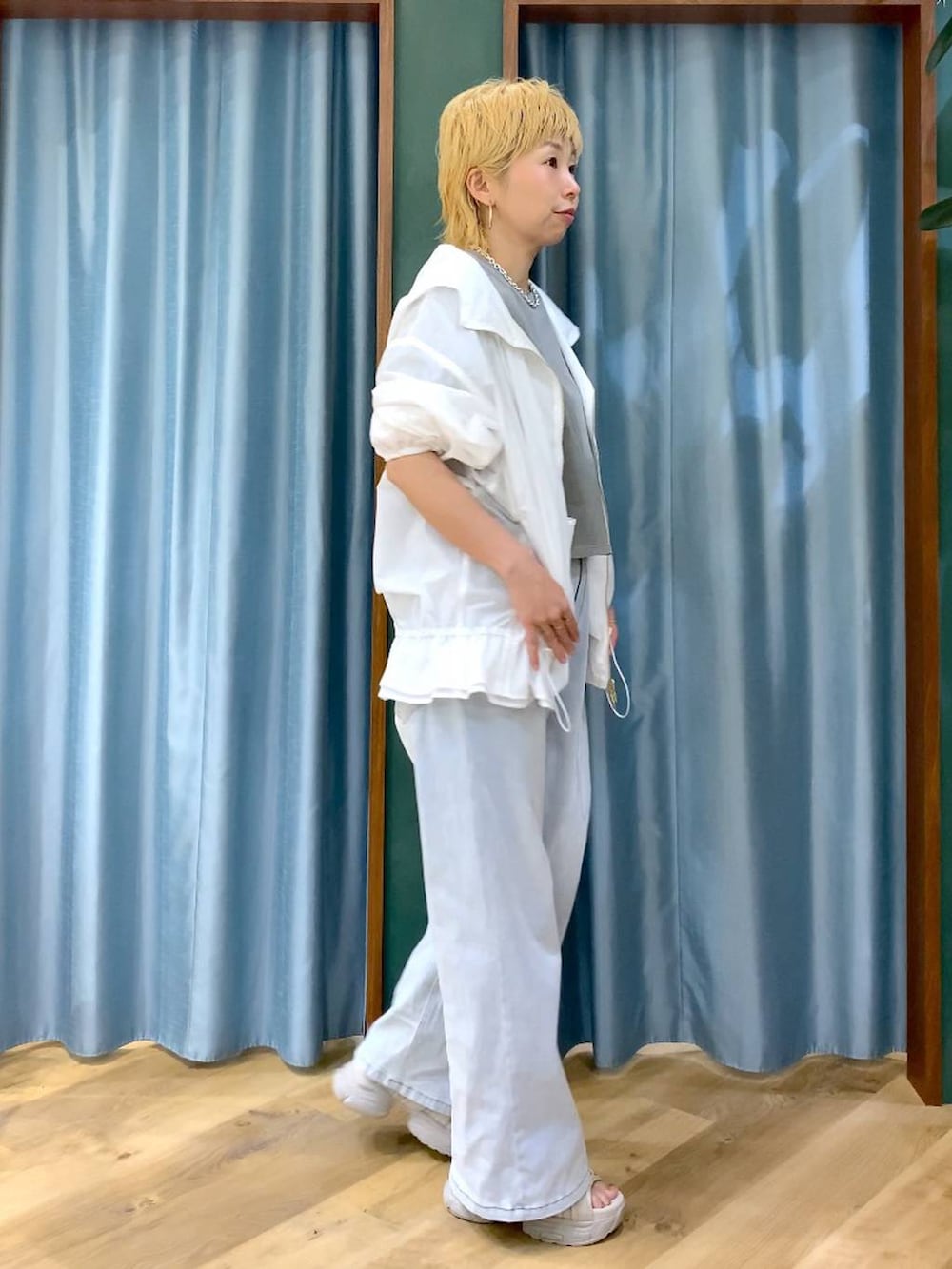 ブルー系のデニムパンツ、グレー系のサンダル、ホワイト系のブルゾンを着用したレディースの春コーディネートの4枚目の写真