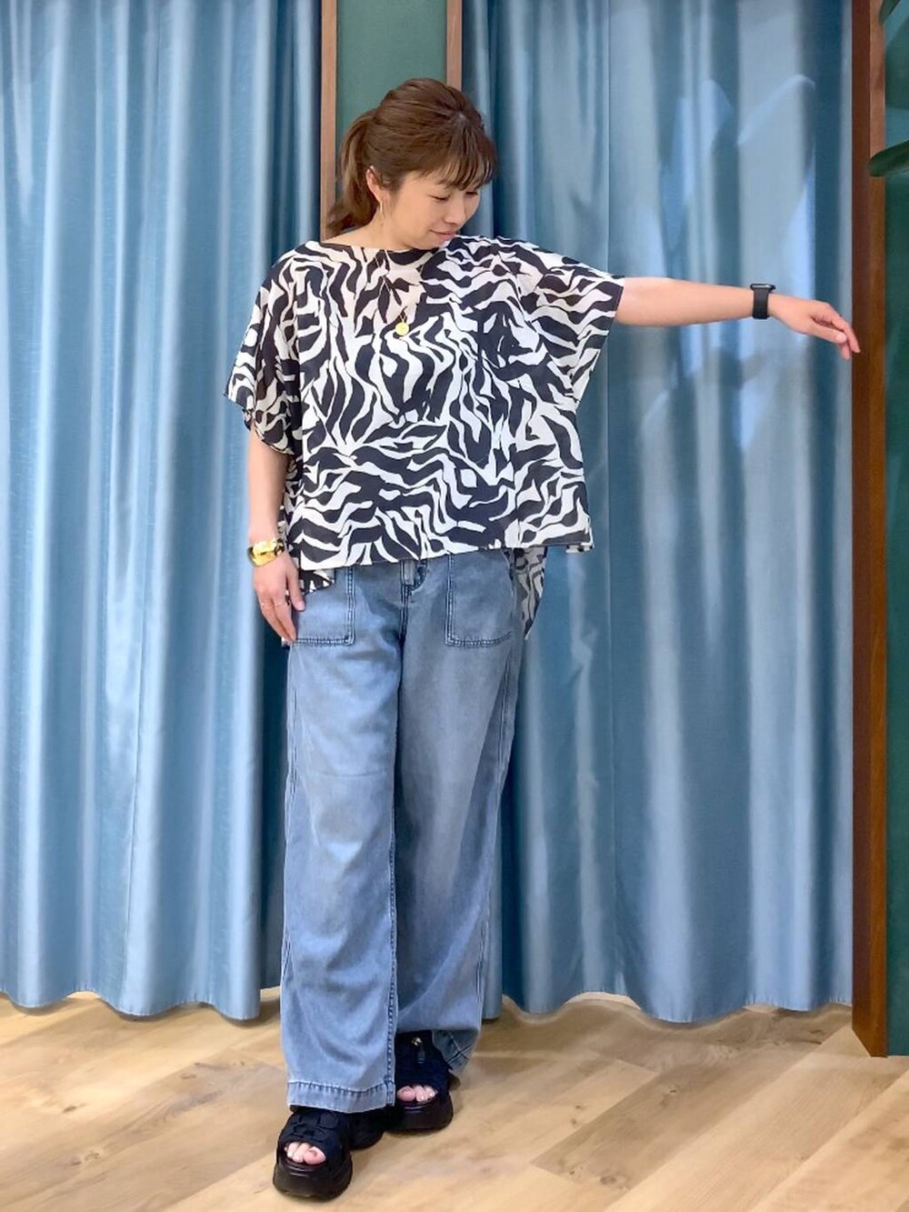 ブルー系のデニムパンツ、ブラック系のシャツ/ブラウス、ブラック系のサンダルを着用したレディースの春コーディネートの3枚目の写真