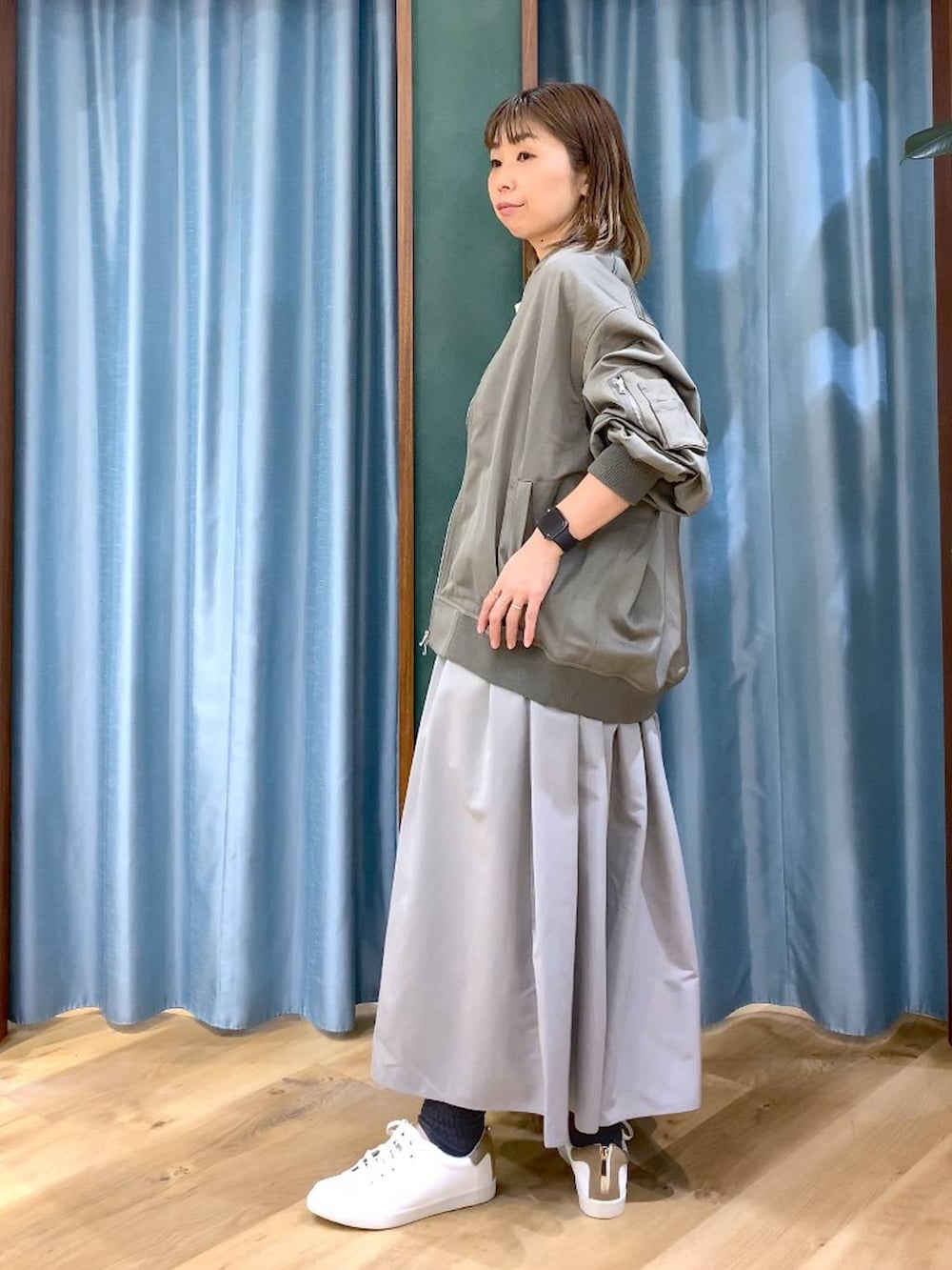 グレー系のスカート、グリーン系のMA-1、ホワイト系のTシャツ/カットソーを着用したレディースの冬コーディネートの3枚目の写真