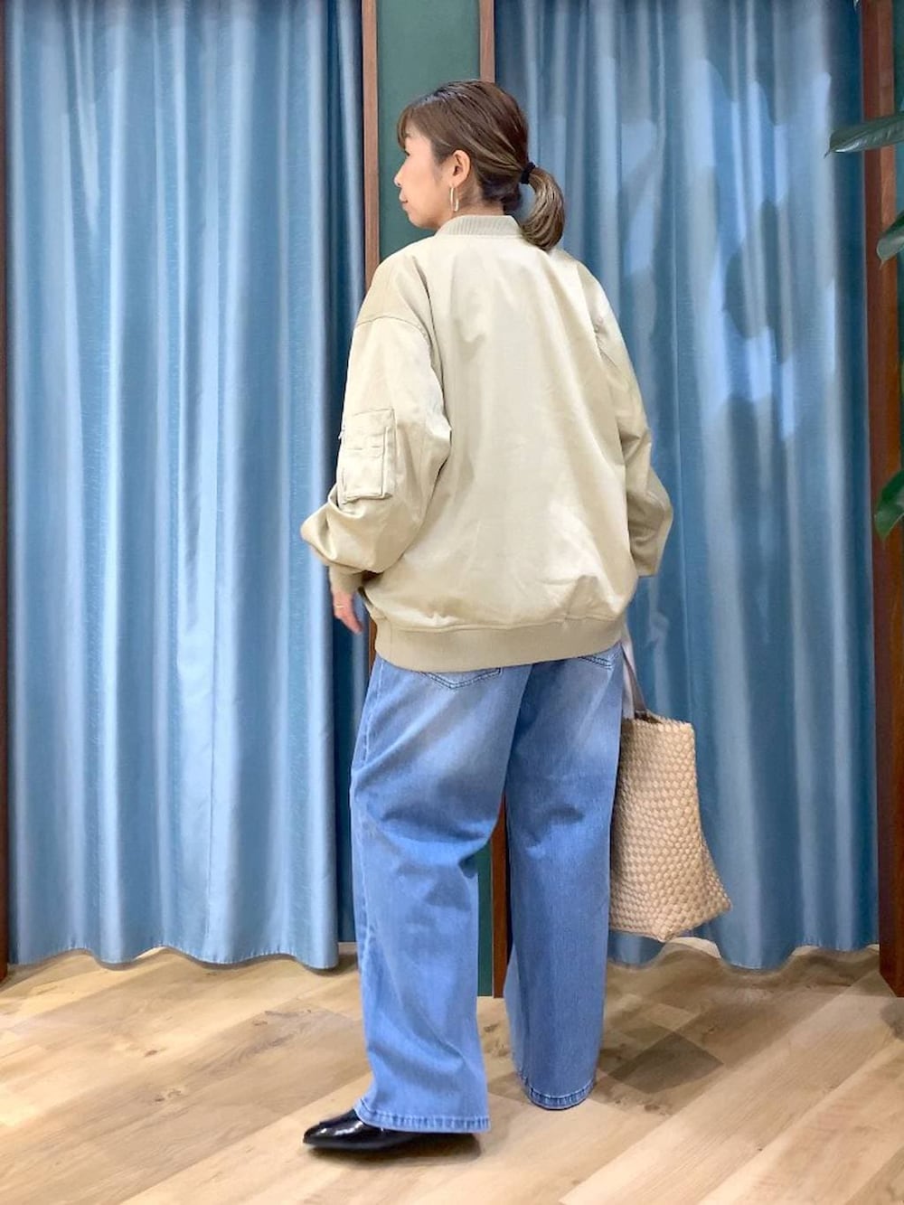 ブルー系のデニムパンツ、ベージュ系のMA-1、グリーン系のTシャツ/カットソーを着用したレディースの冬コーディネートの5枚目の写真