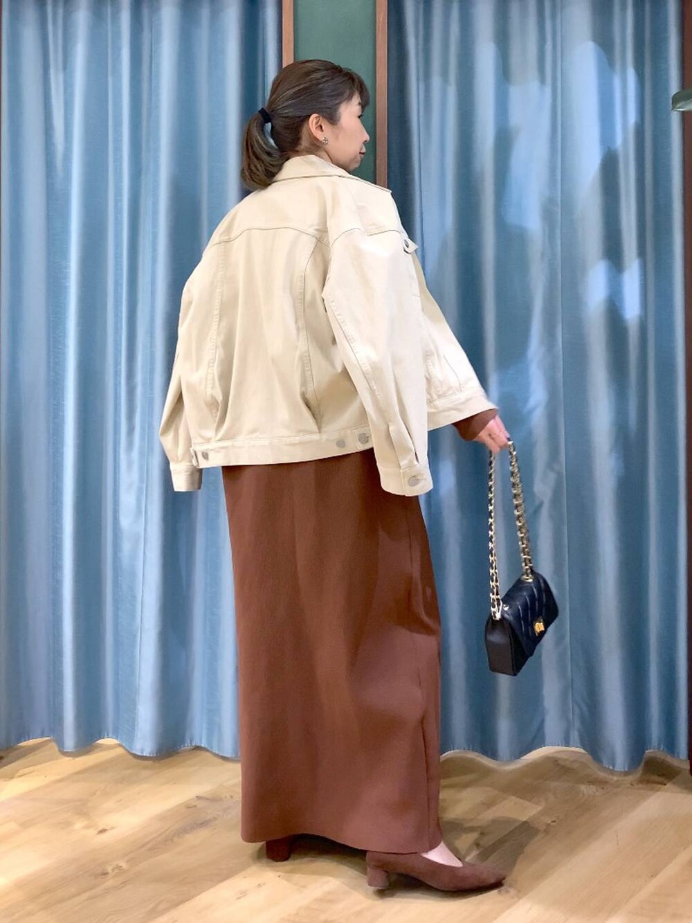 ブラウン系のパンプス、ベージュ系のデニムジャケット、ブラウン系のワンピースを着用したレディースの冬コーディネートの6枚目の写真