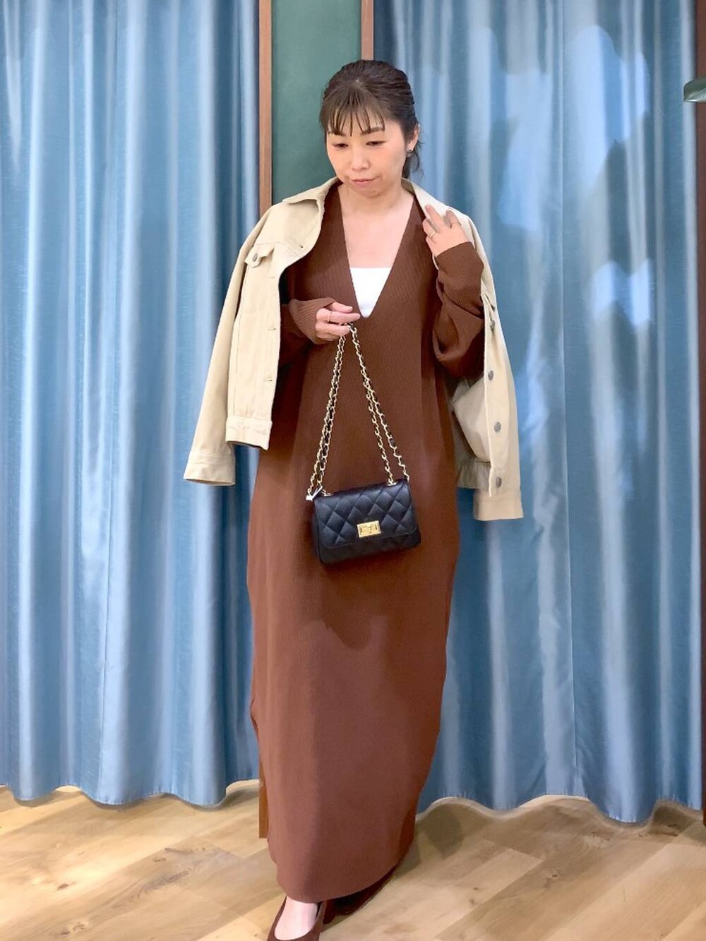 ブラウン系のパンプス、ベージュ系のデニムジャケット、ブラウン系のワンピースを着用したレディースの冬コーディネートの2枚目の写真