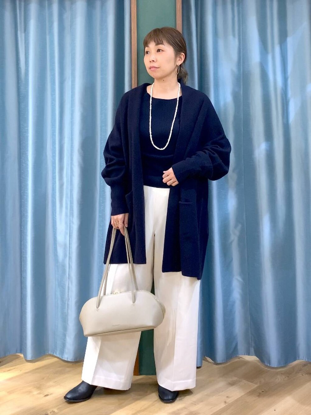 ベージュ系のトートバッグ、ブラック系のブーツ、ブルー系のニット/セーターを着用したレディースの冬コーディネートの5枚目の写真