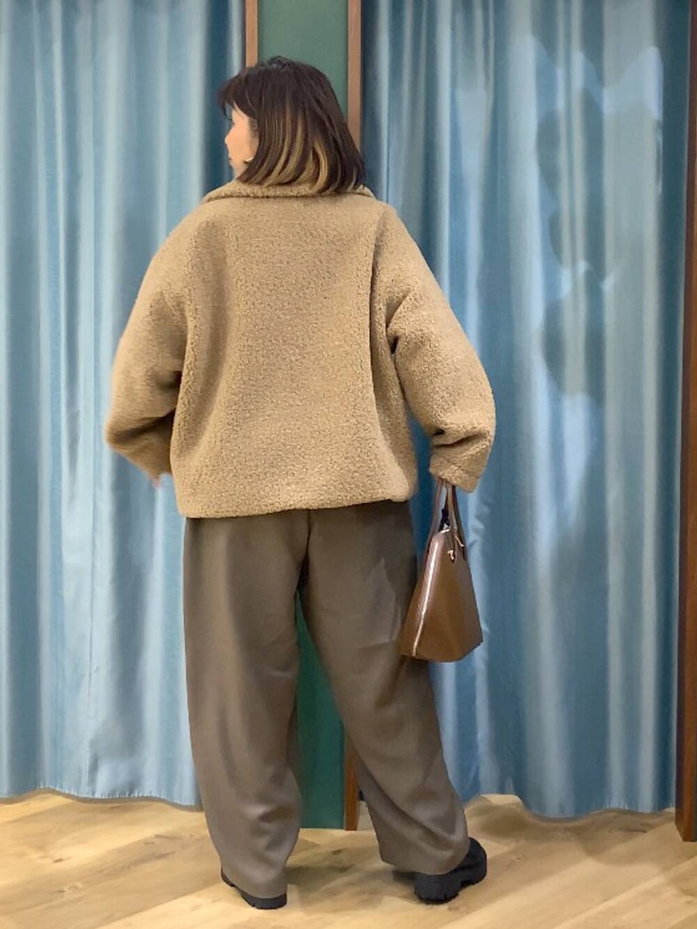 ブラック系のブーツ、ベージュ系のピーコート、ブラウン系のトートバッグを着用したレディースの秋コーディネートの6枚目の写真