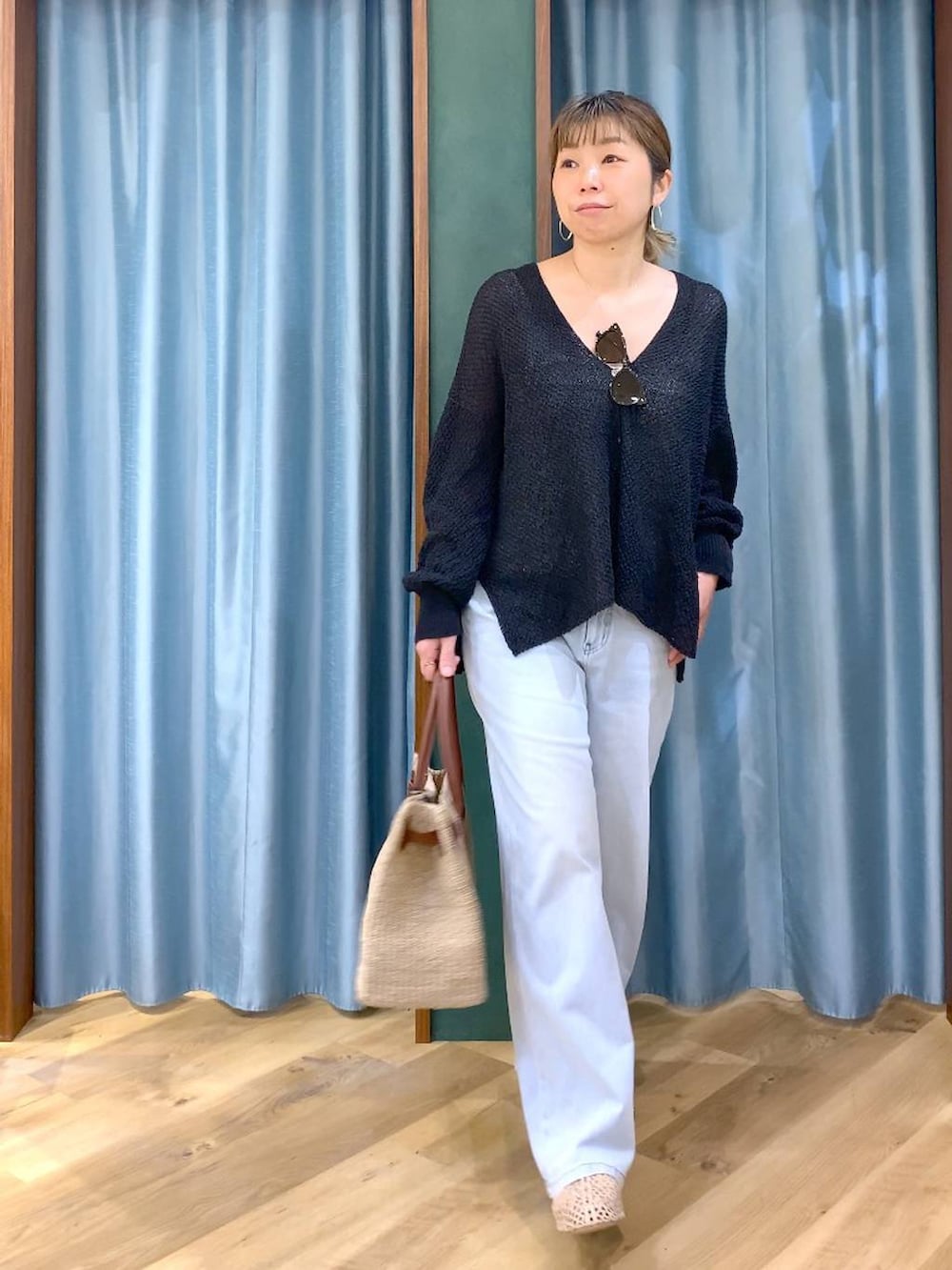 ホワイト系のタンクトップ、ブルー系のデニムパンツ、ブラック系のカーディガン/ボレロを着用したレディースの春コーディネートの2枚目の写真