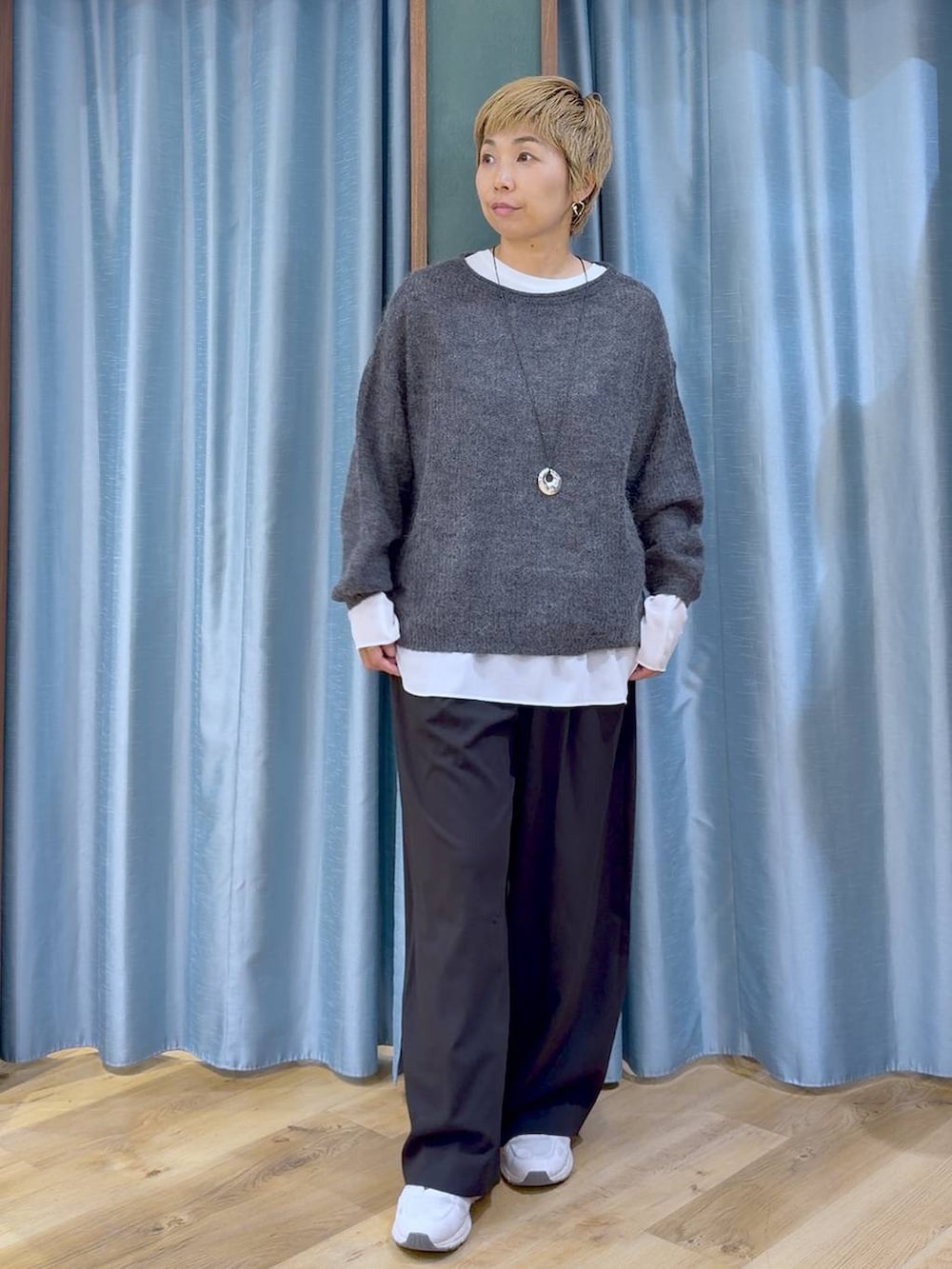 グレー系のニット/セーター、ブラック系のその他パンツ、ホワイト系のTシャツ/カットソーを着用したレディースの秋コーディネートの2枚目の写真