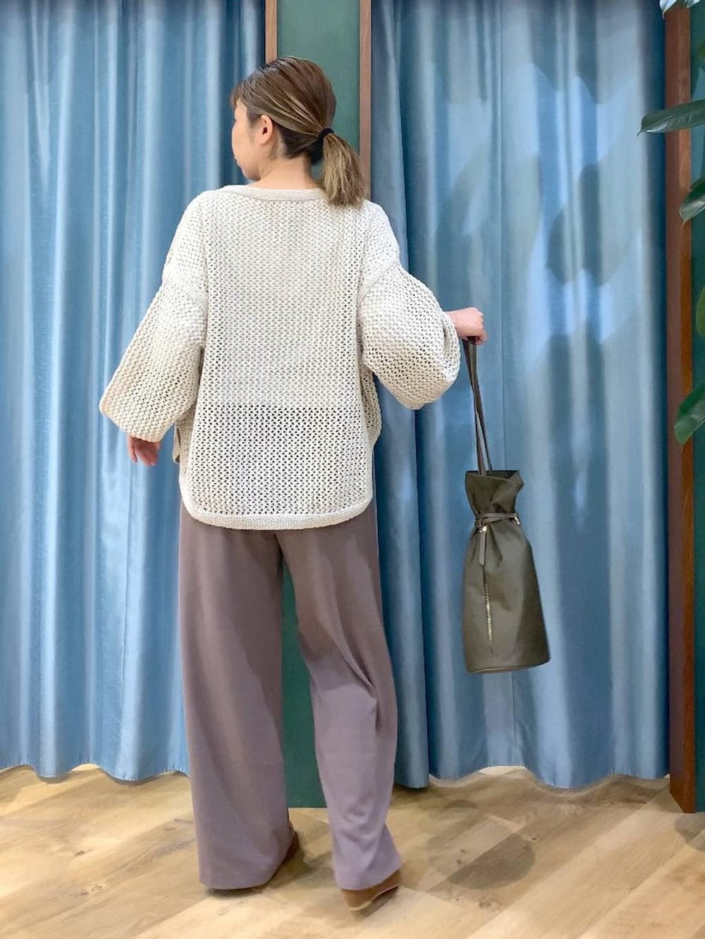 グリーン系のスラックス、ベージュ系のニット/セーター、ホワイト系のTシャツ/カットソーを着用したレディースの冬コーディネートの5枚目の写真