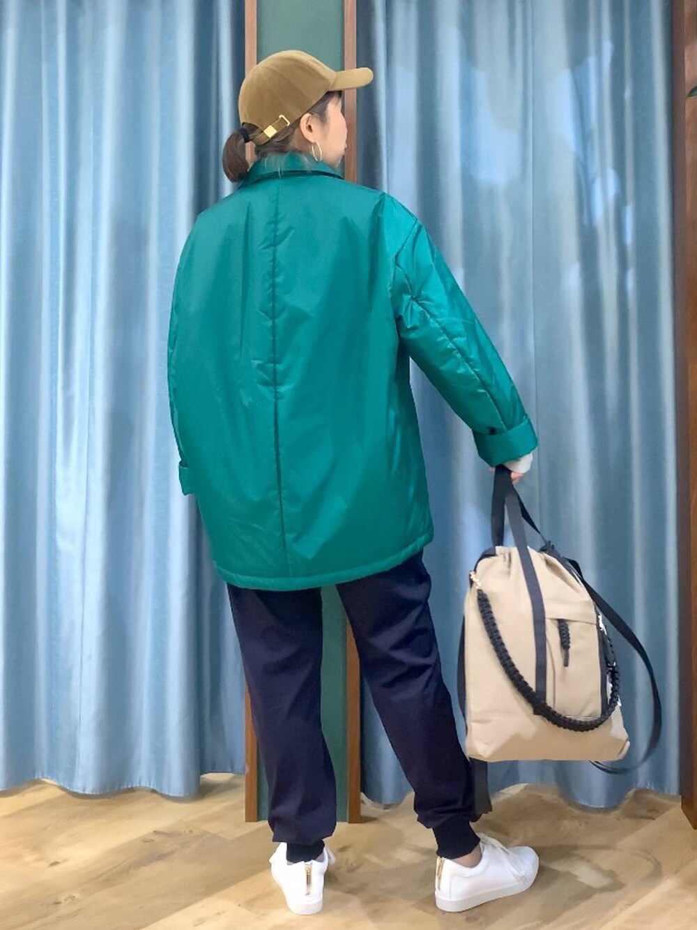 グリーン系のブルゾン、ブルー系のその他パンツ、ブラウン系のバックパック/リュックを着用したレディースの秋コーディネートの4枚目の写真