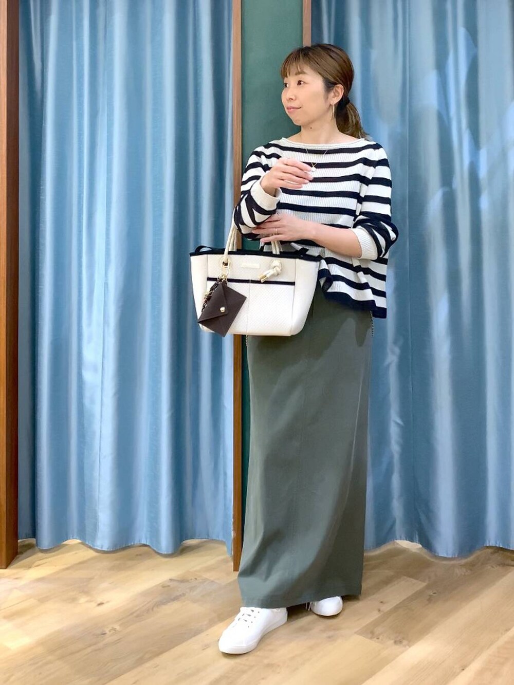 ベージュ系のニット/セーター、グリーン系のスカート、ホワイト系のトートバッグを着用したレディースの春コーディネートの3枚目の写真