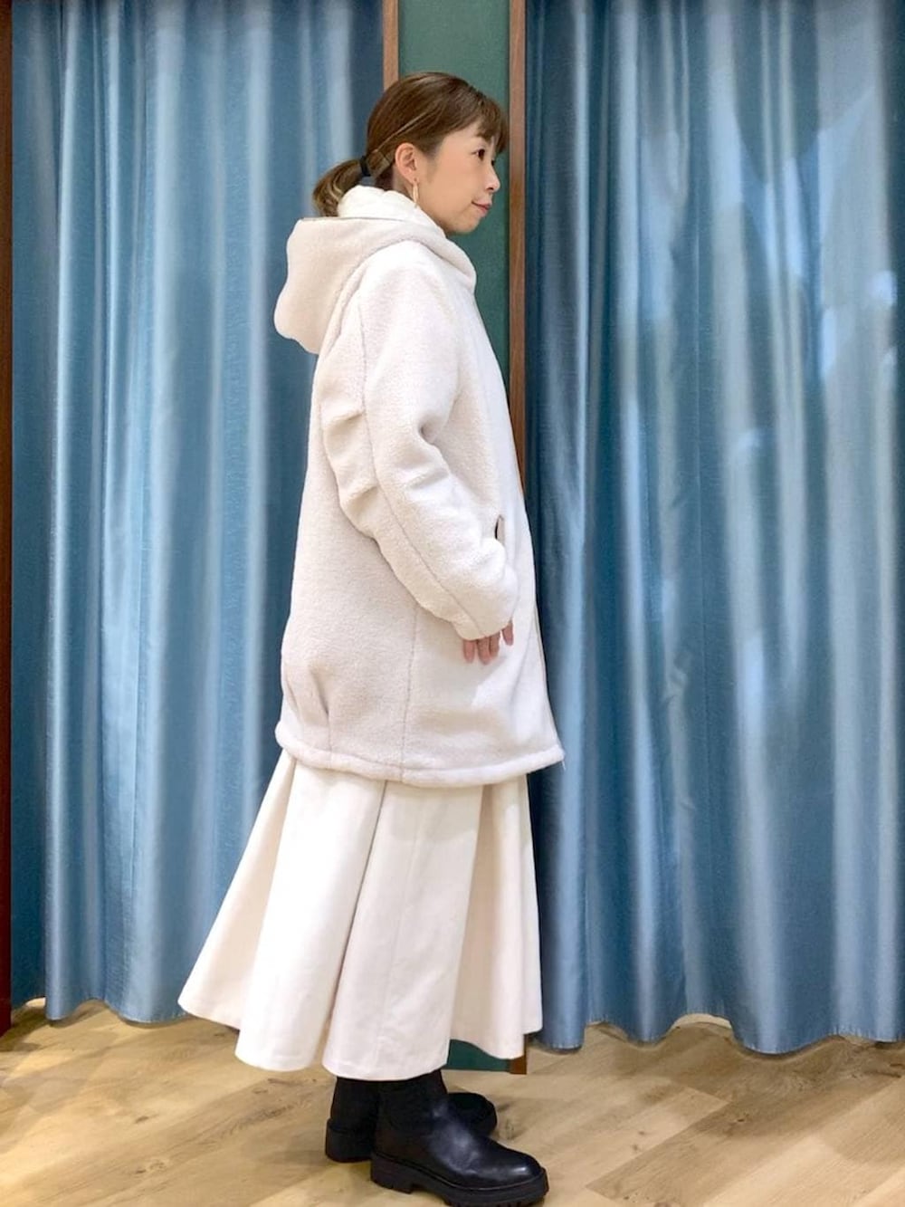 ブラック系のブーツ、ホワイト系のその他アウター、ホワイト系のスカートを着用したレディースの冬コーディネートの3枚目の写真