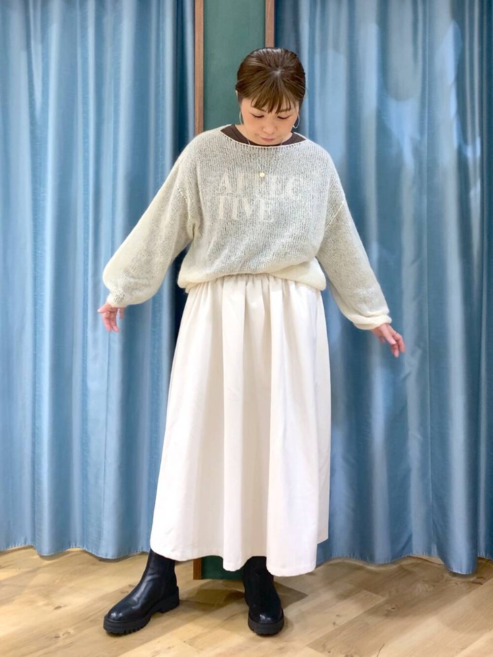 ブラック系のブーツ、ホワイト系のスカート、ホワイト系のニット/セーターを着用したレディースの冬コーディネートの2枚目の写真