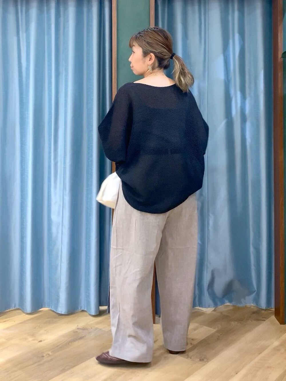 ブラック系のニット/セーター、ベージュ系のその他パンツ、ホワイト系のトートバッグを着用したレディースの春コーディネートの6枚目の写真