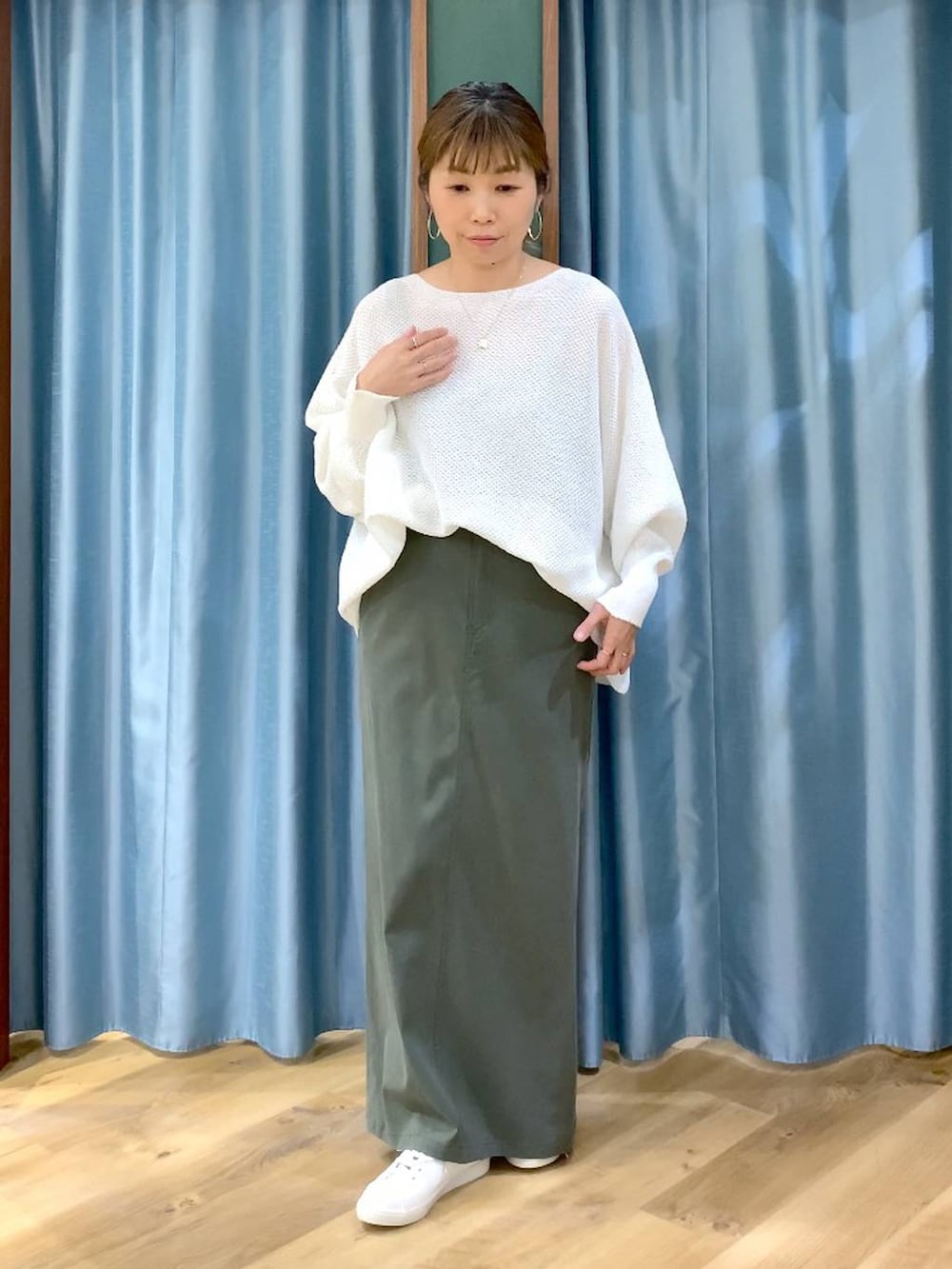 ホワイト系のニット/セーター、グリーン系のスカート、ブラウン系のスニーカーを着用したレディースの春コーディネートの2枚目の写真