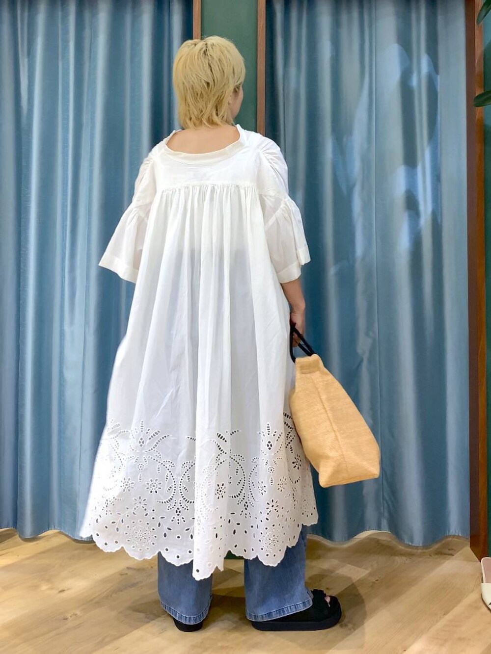 ブルー系のデニムパンツ、ブラック系のサンダル、ベージュ系のトートバッグを着用したレディースの夏コーディネートの5枚目の写真
