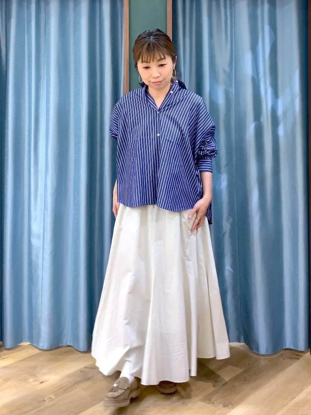 ベージュ系のローファー、ホワイト系のスカート、ブルー系のシャツ/ブラウスを着用したレディースの春コーディネートの2枚目の写真