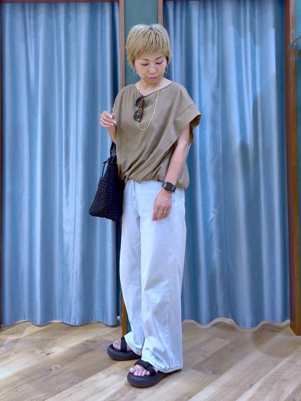 ブラック系のトートバッグ、ブルー系のデニムパンツ、ブラック系のサンダルを着用したレディースの夏コーディネートの4枚目の写真