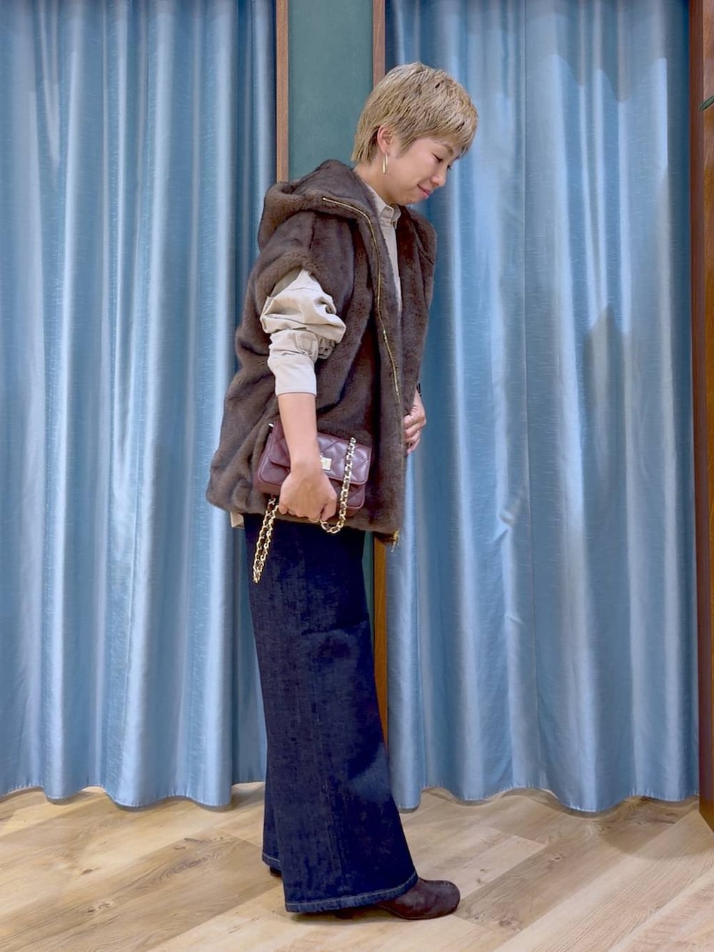 ブラウン系のブーツ、ブラウン系のハンドバッグ、ブルー系のデニムパンツを着用したレディースの秋コーディネートの2枚目の写真