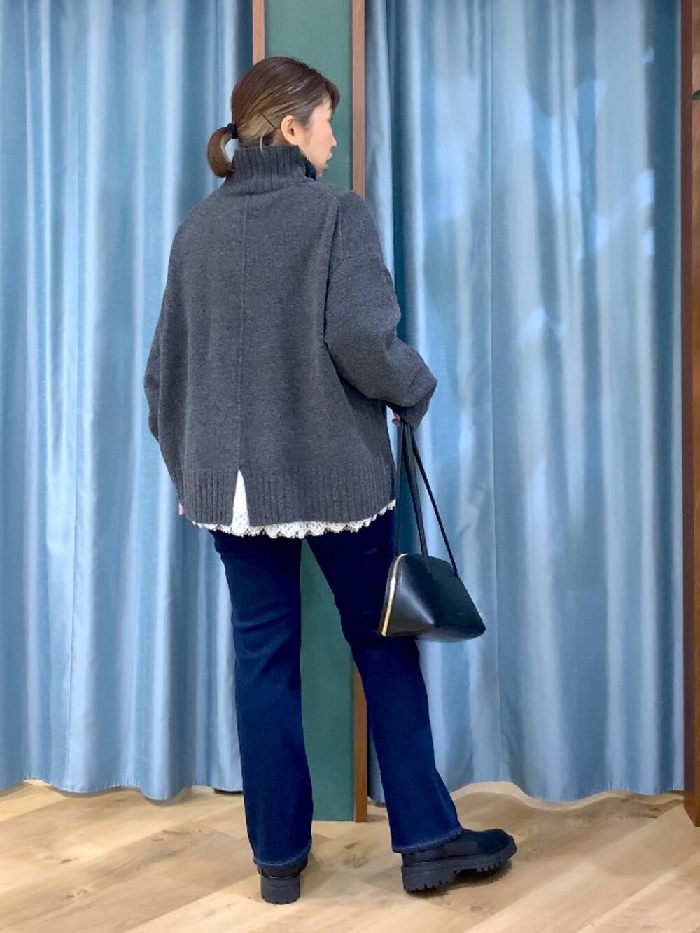 ブラック系のトートバッグ、ブラック系のブーツ、ブルー系のデニムパンツを着用したレディースの秋コーディネートの4枚目の写真