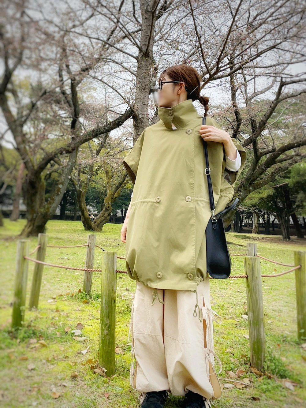 ブラック系のショルダーバッグ、グリーン系のモッズコート、ホワイト系のTシャツ/カットソーを着用したレディースの春コーディネートの2枚目の写真