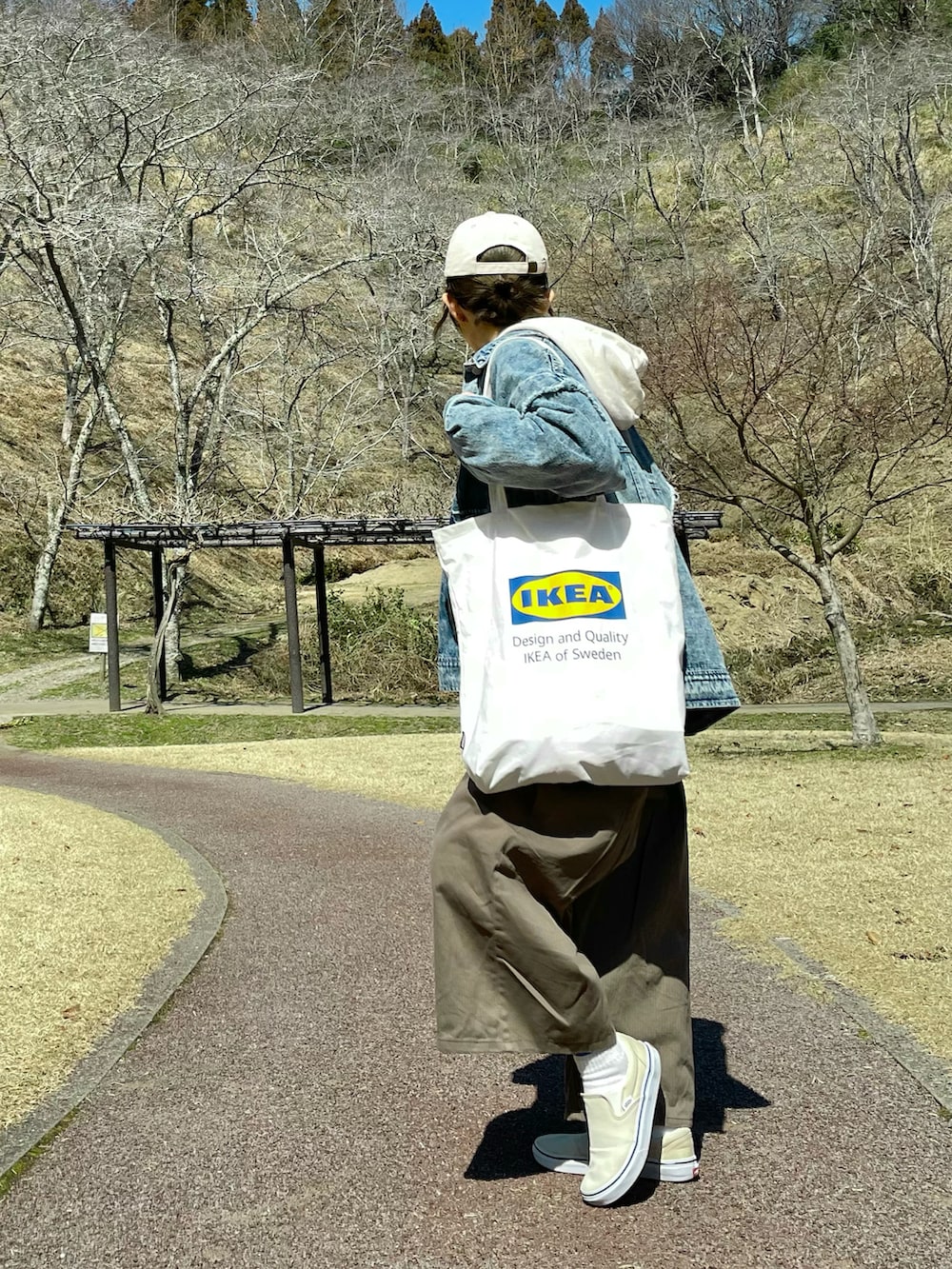 ホワイト系のトートバッグ、ブルー系のデニムジャケット、グリーン系のサロペット/オーバーオールを着用したレディースの春コーディネートの3枚目の写真