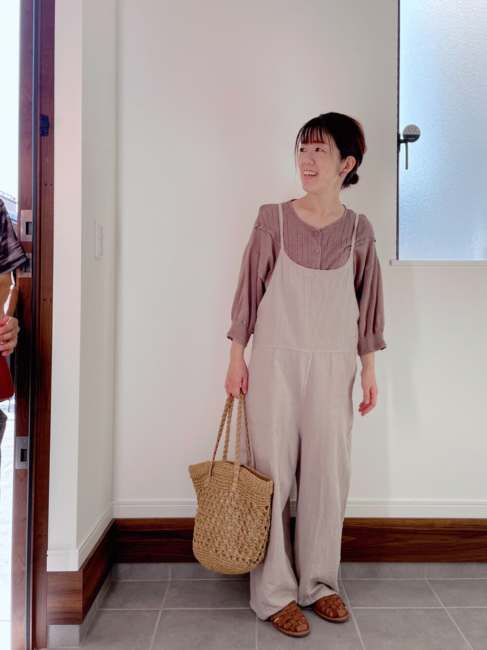 イエロー系のかごバッグ、ブラウン系のカーディガン/ボレロ、ベージュ系のサロペット/オーバーオールを着用したレディースの夏コーディネートの2枚目の写真