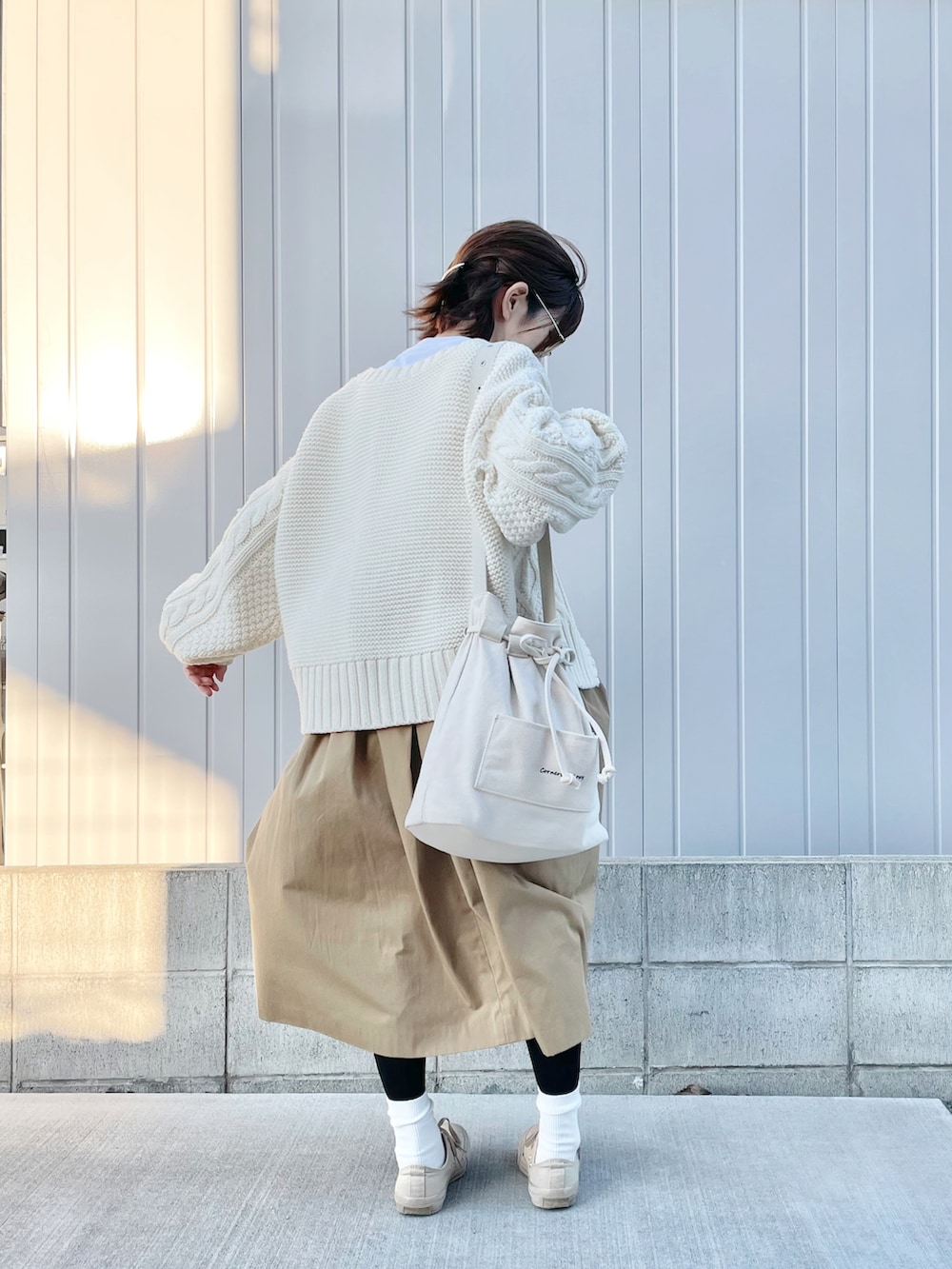 ベージュ系のスカート、ホワイト系のTシャツ/カットソー、ホワイト系のカーディガン/ボレロを着用したレディースの秋コーディネートの3枚目の写真