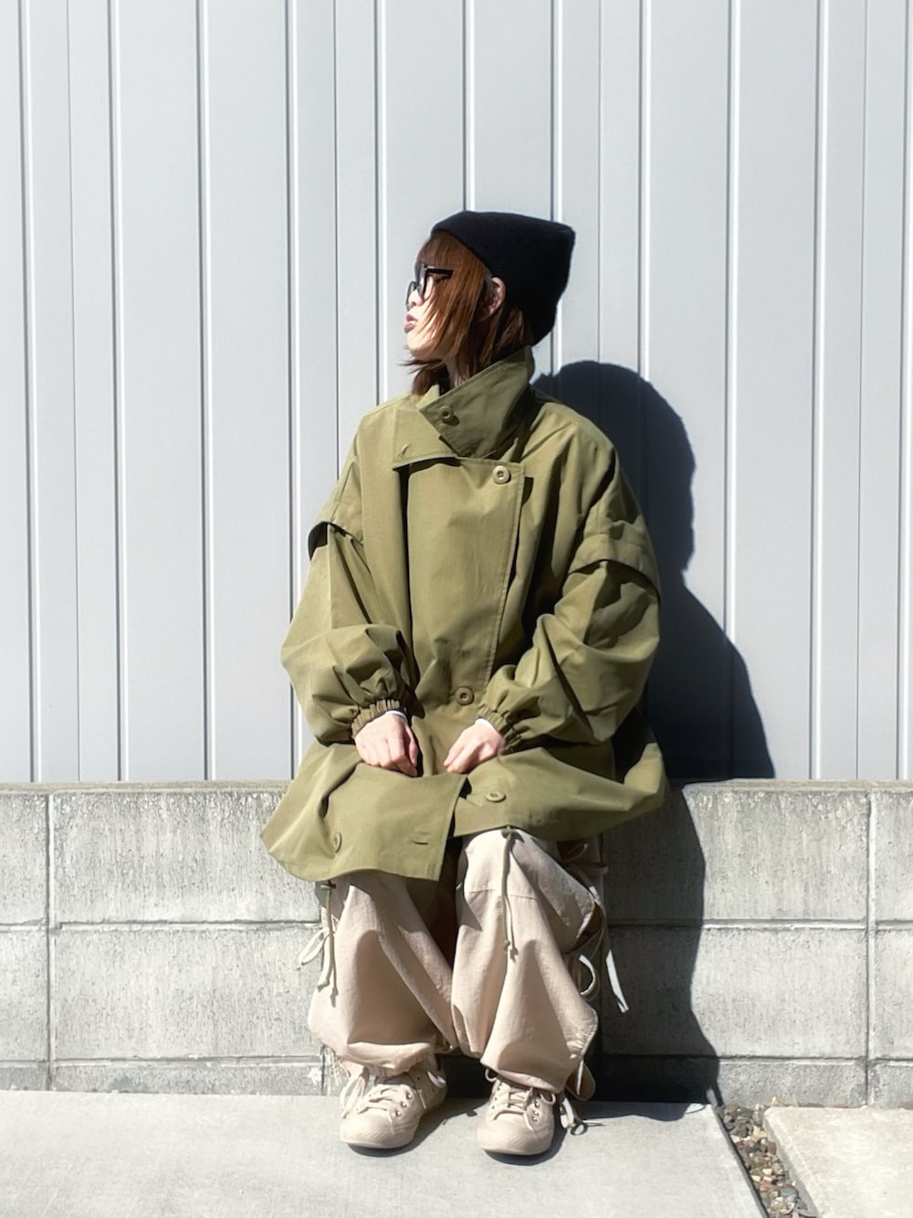 ベージュ系のカーゴパンツ、ホワイト系のTシャツ/カットソー、グリーン系のモッズコートを着用したレディースの春コーディネートの2枚目の写真