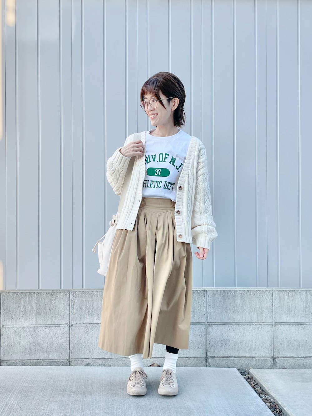 ベージュ系のスカート、ホワイト系のTシャツ/カットソー、ホワイト系のカーディガン/ボレロを着用したレディースの秋コーディネートの2枚目の写真