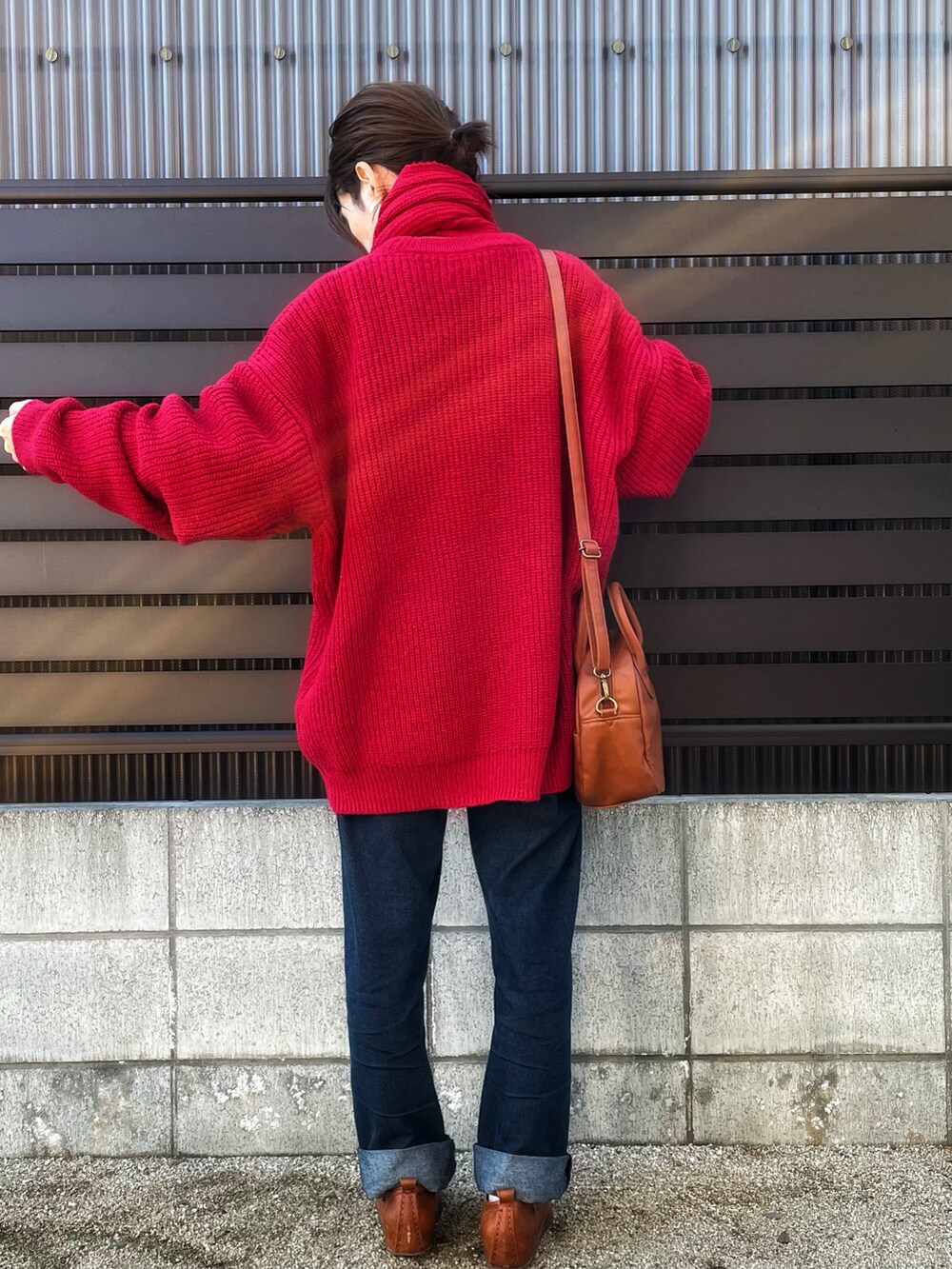 レッド系のニット/セーター、イエロー系のショルダーバッグ、ブルー系のデニムパンツを着用したレディースの秋コーディネートの2枚目の写真