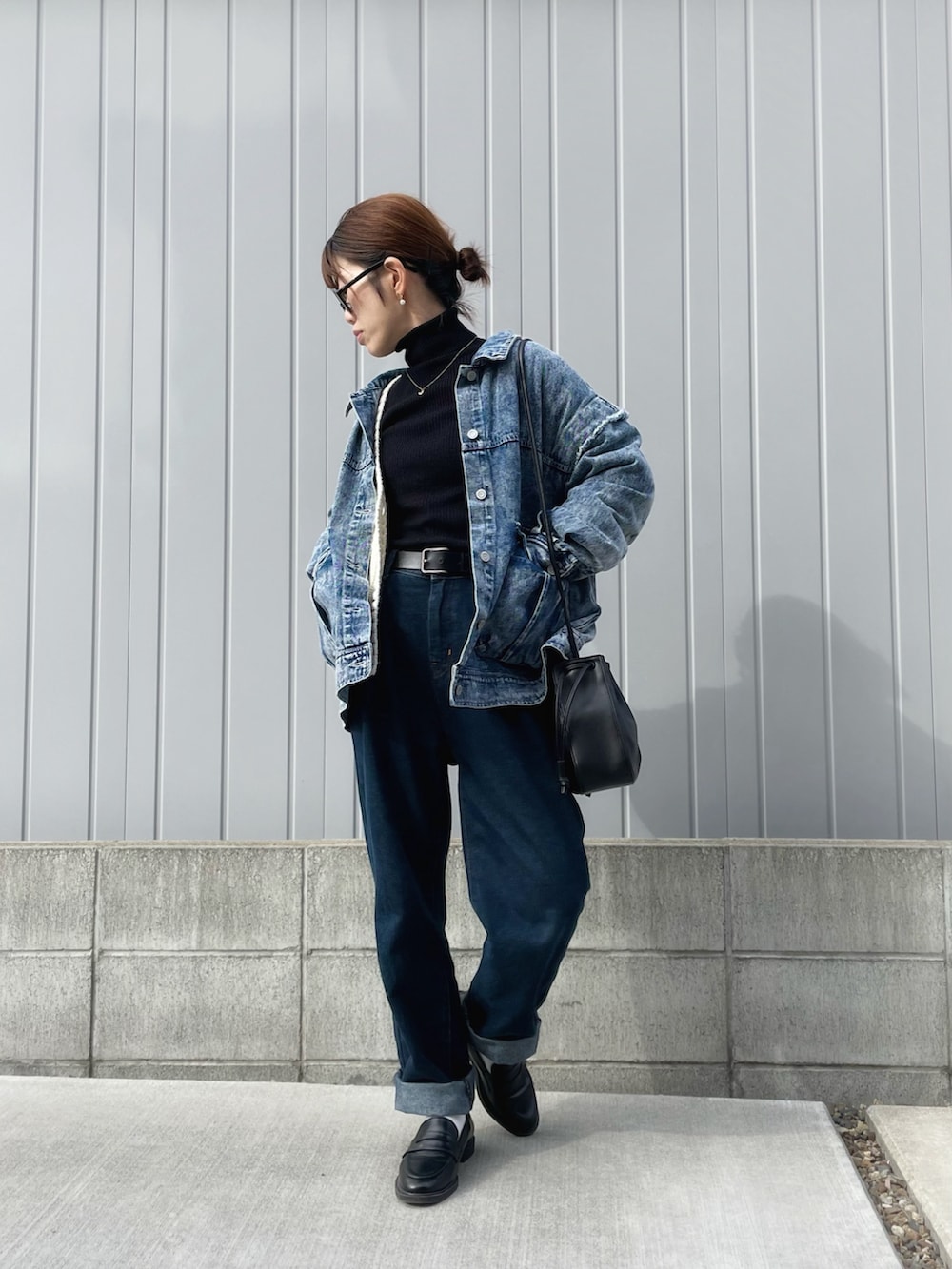 ブルー系のデニムパンツ、ブラック系のショルダーバッグ、ブルー系のデニムジャケットを着用したレディースの冬コーディネートの2枚目の写真