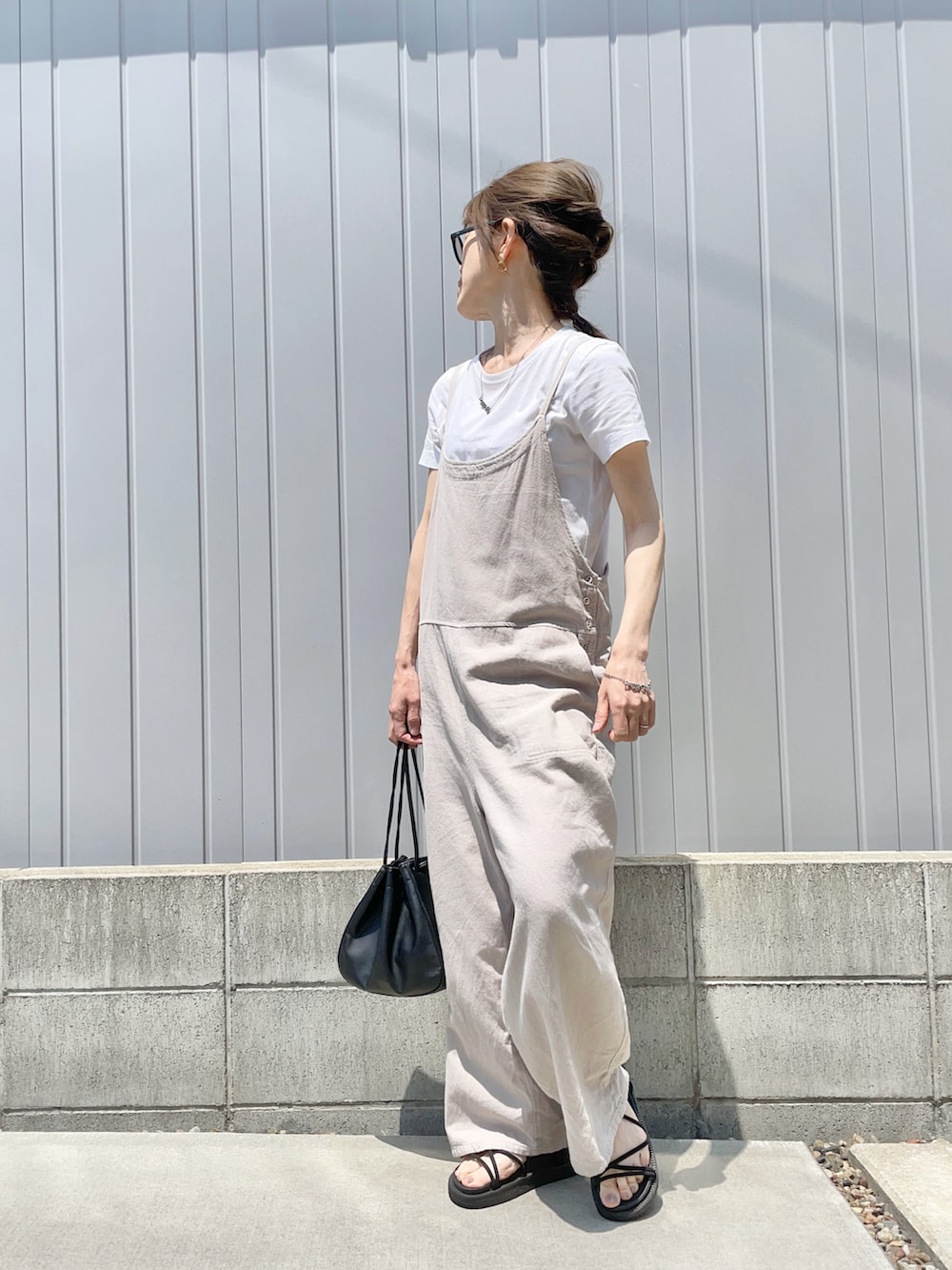 ブラック系のバッグ、ブラック系のサンダル、ホワイト系のTシャツ/カットソーを着用したレディースの春コーディネートの2枚目の写真