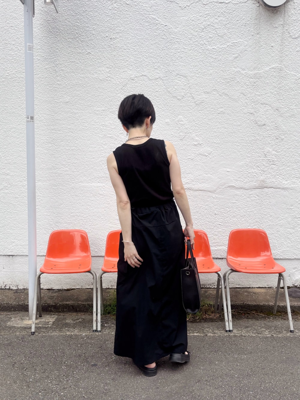 ブラック系のサンダル、ブラック系のショルダーバッグ、ブラック系のジャンパースカートを着用したレディースの夏コーディネートの2枚目の写真