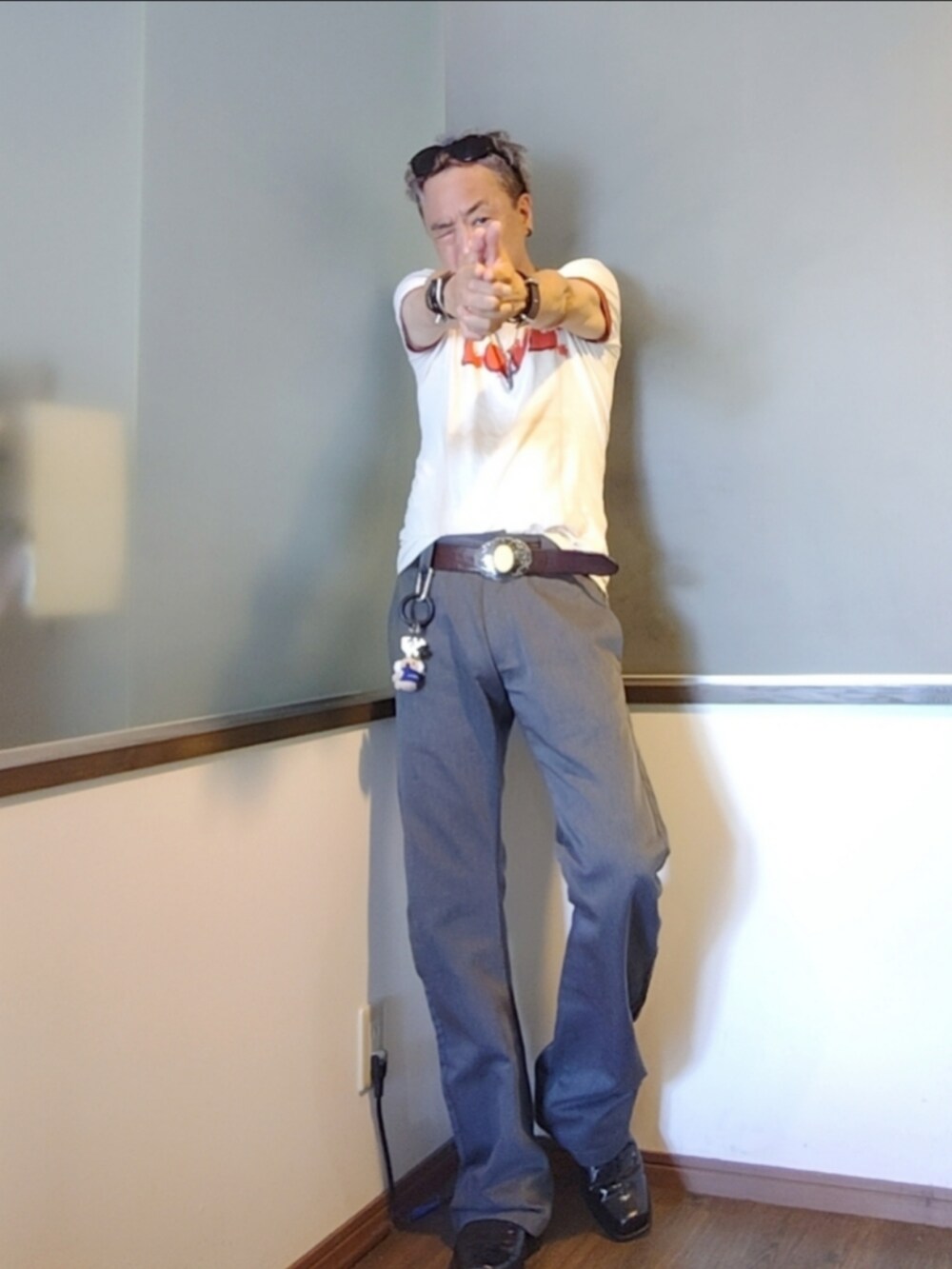 ベージュ系のTシャツ/カットソー、グレー系のチノパンツ、ブラック系のブーツを着用したメンズの夏コーディネートの3枚目の写真