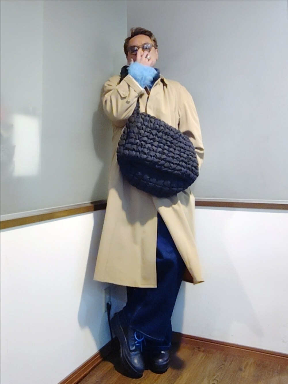 ブルー系のニット/セーター、ピンク系のTシャツ/カットソー、ベージュ系のトレンチコートを着用したメンズの秋コーディネートの2枚目の写真