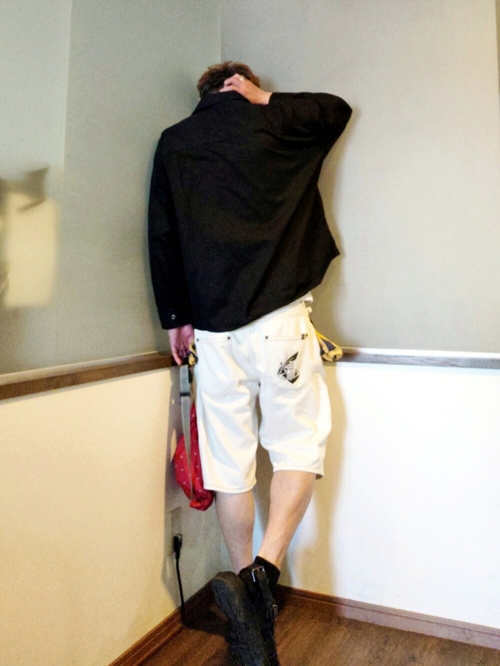 ホワイト系のデニムパンツ、レッド系のショルダーバッグ、ブラック系のサンダルを着用したメンズの夏コーディネートの2枚目の写真