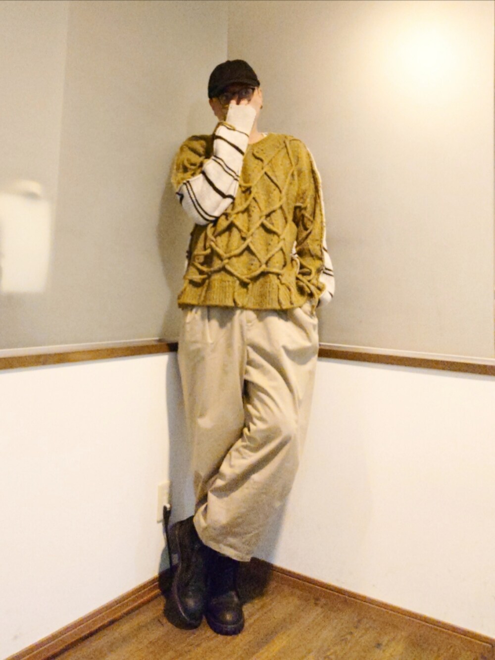 グリーン系のニット/セーター、ブラック系のピーコート、ベージュ系のチノパンツを着用したメンズの冬コーディネートの4枚目の写真