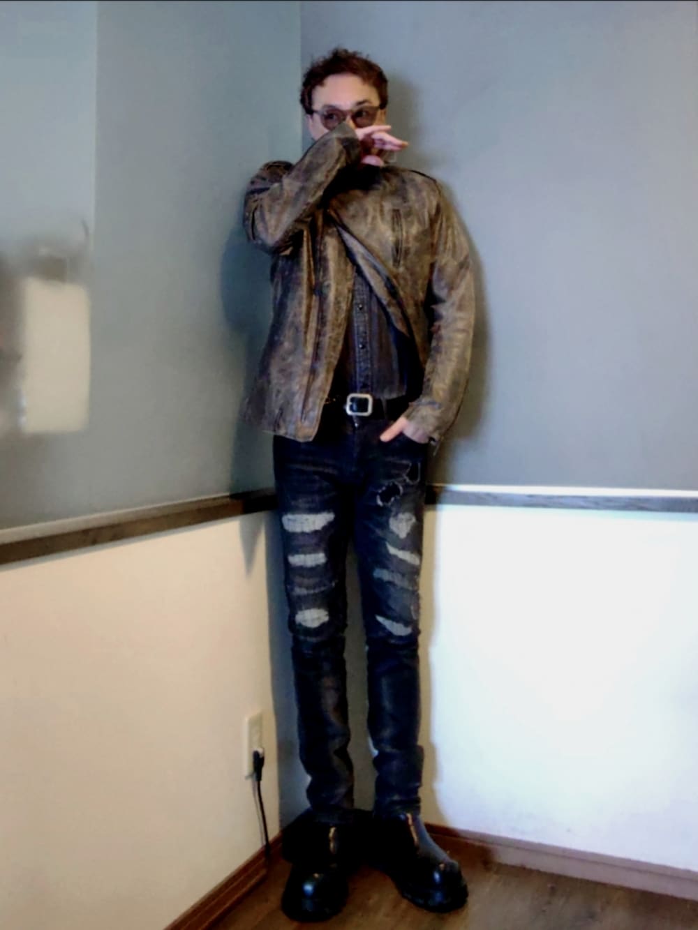 ブラック系のデニムパンツ、ブラック系のブーツ、ブラウン系のライダースジャケットを着用したメンズの春コーディネートの3枚目の写真